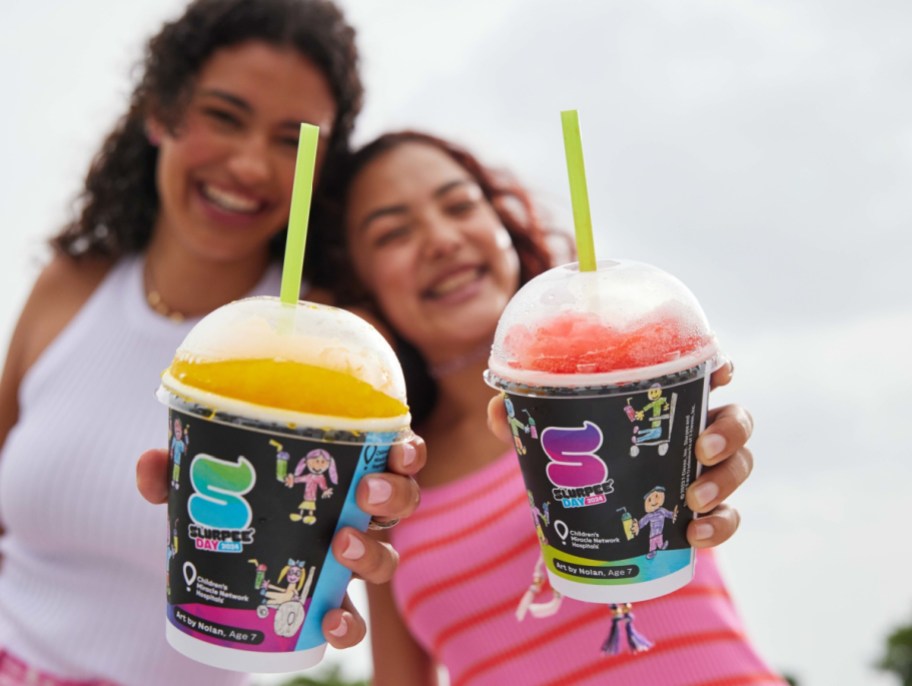 Girls holding up a slurpee cup that lifts up pediatric cancer patients