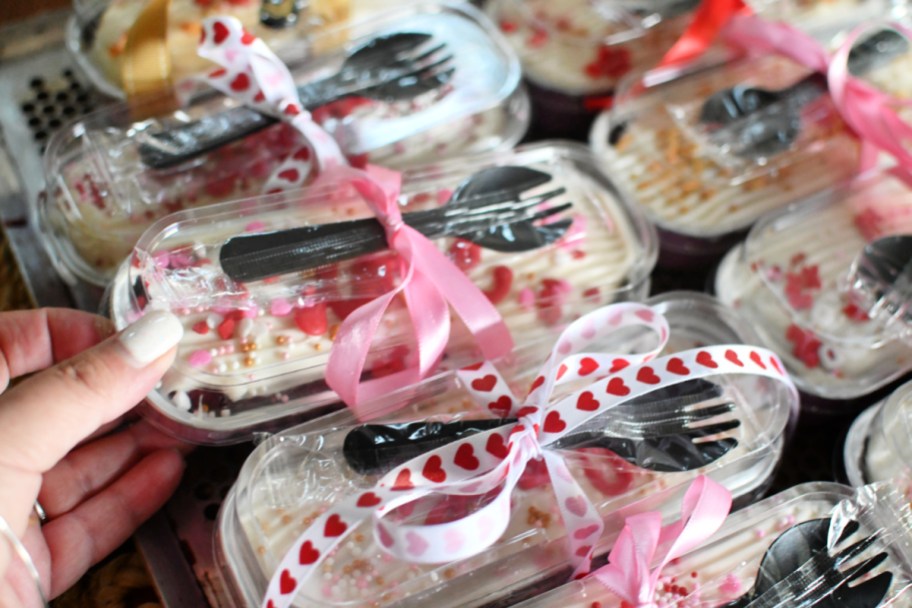 holding a wrapped valentines day cake with fork