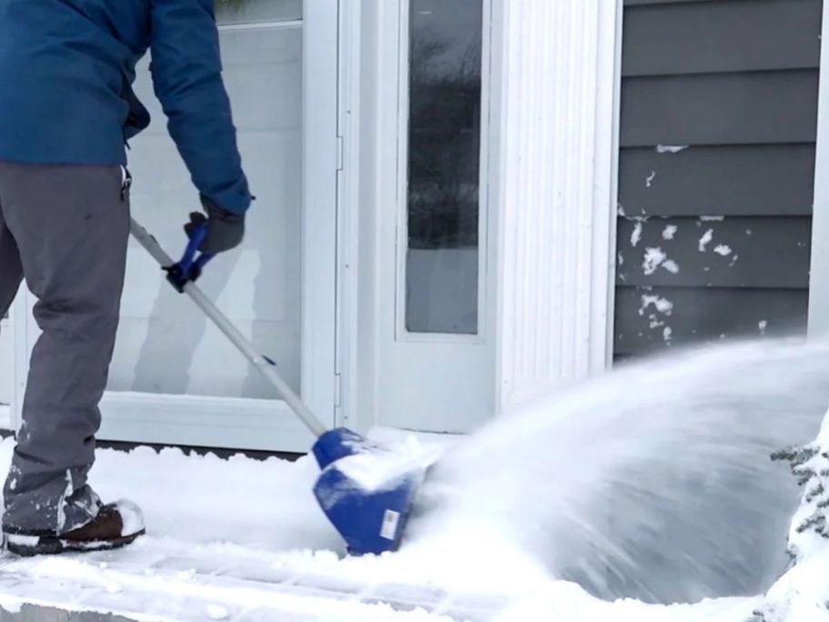 person using Snow Joe 24-Volt Cordless Snow Shovel w/ Bonus Cover on snow on doorstep