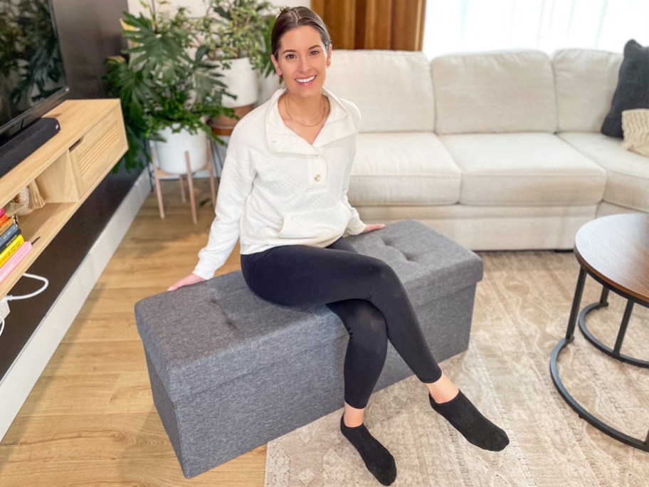 woman sitting on a grey storage ottoman