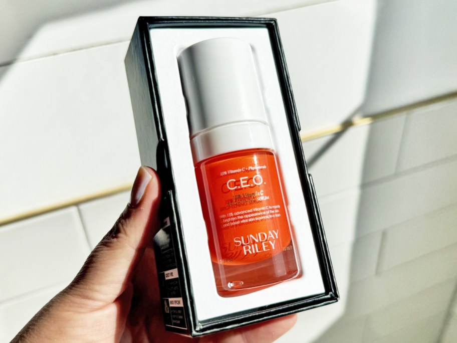 hand holding a boxed orange bottle of Sunday Riley C.E.O. 15% Vitamin C Brightening Serum