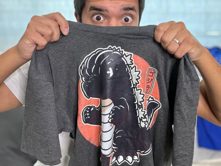 man peeking out from behind a graphic tee from Woot!