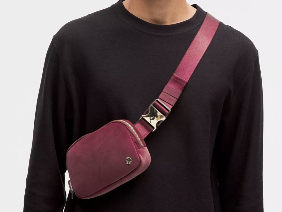 person in a black long sleeve top with maroon belt bad across chest