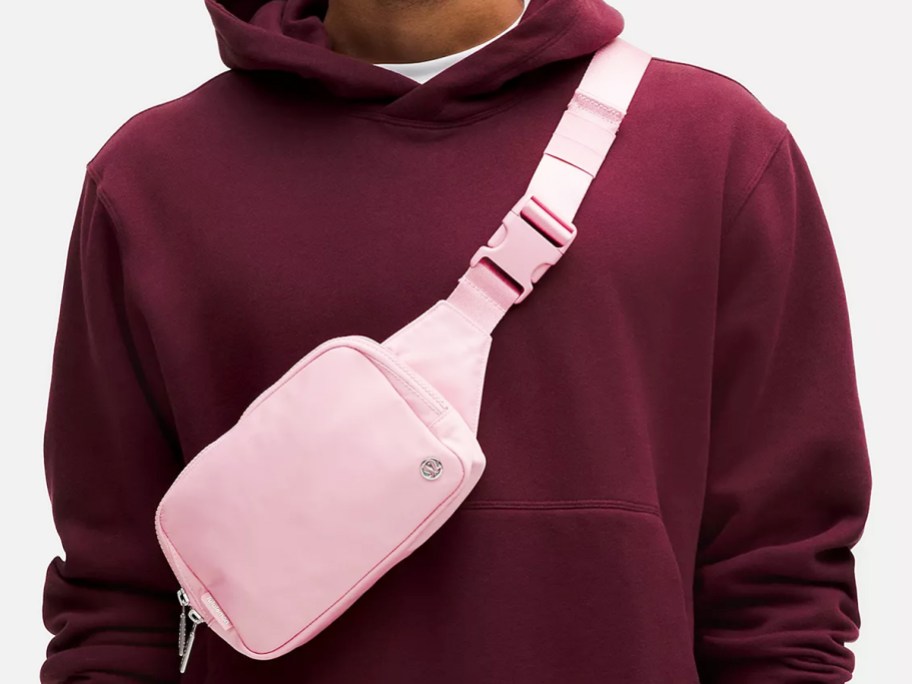 man in maroon hoodie with pink belt bag across chest