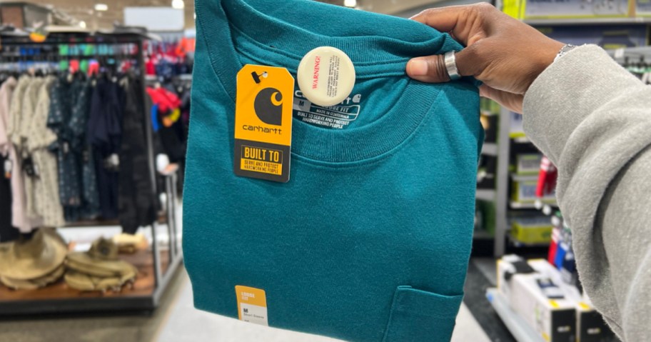 hand holding blue carhartt pocket tee