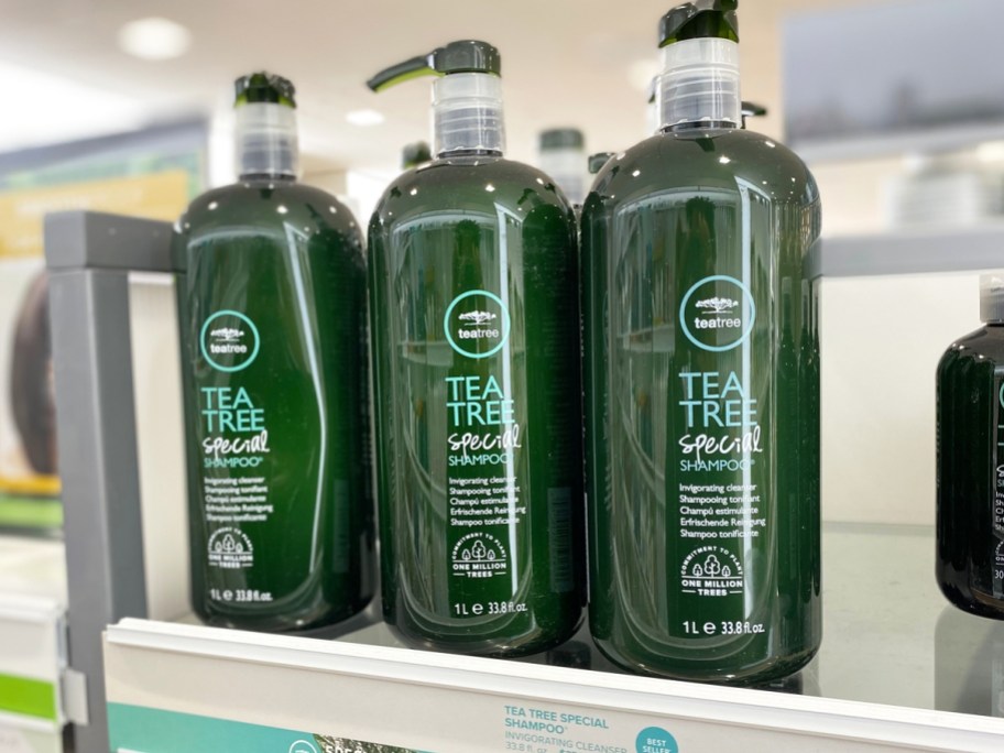 3 large green bottles of Paul Mitchell Tea Tree Shampoo on store shelf