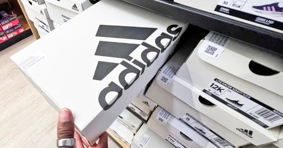 hand grabbing a white adidas shoe box from store shelf