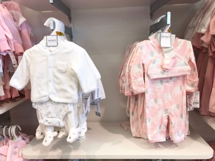 baby clothing sets hanging on a rack in a store