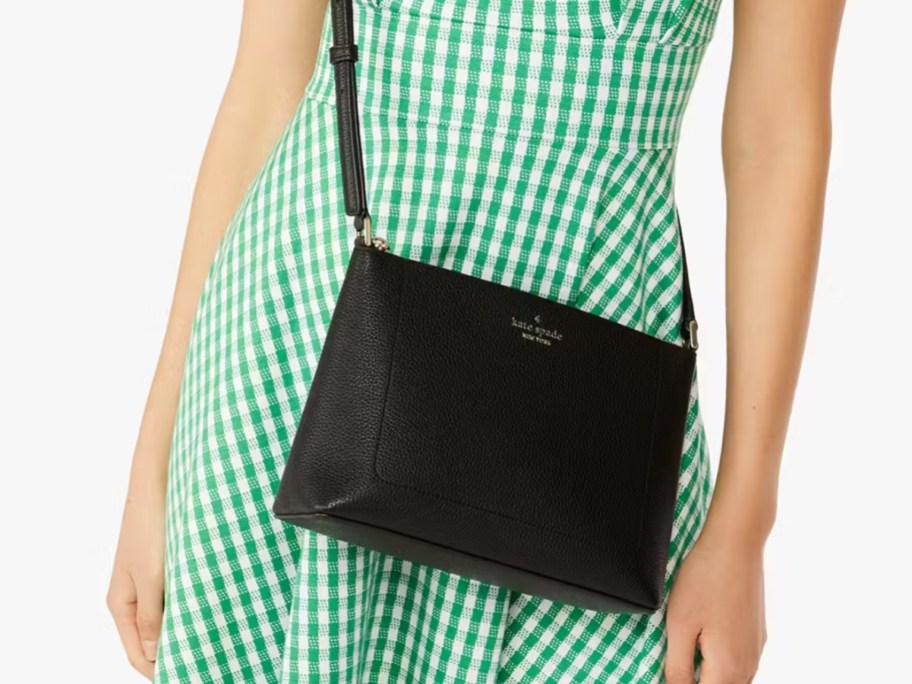 woman wearing a green and white gingham dress with a black crossbody purse