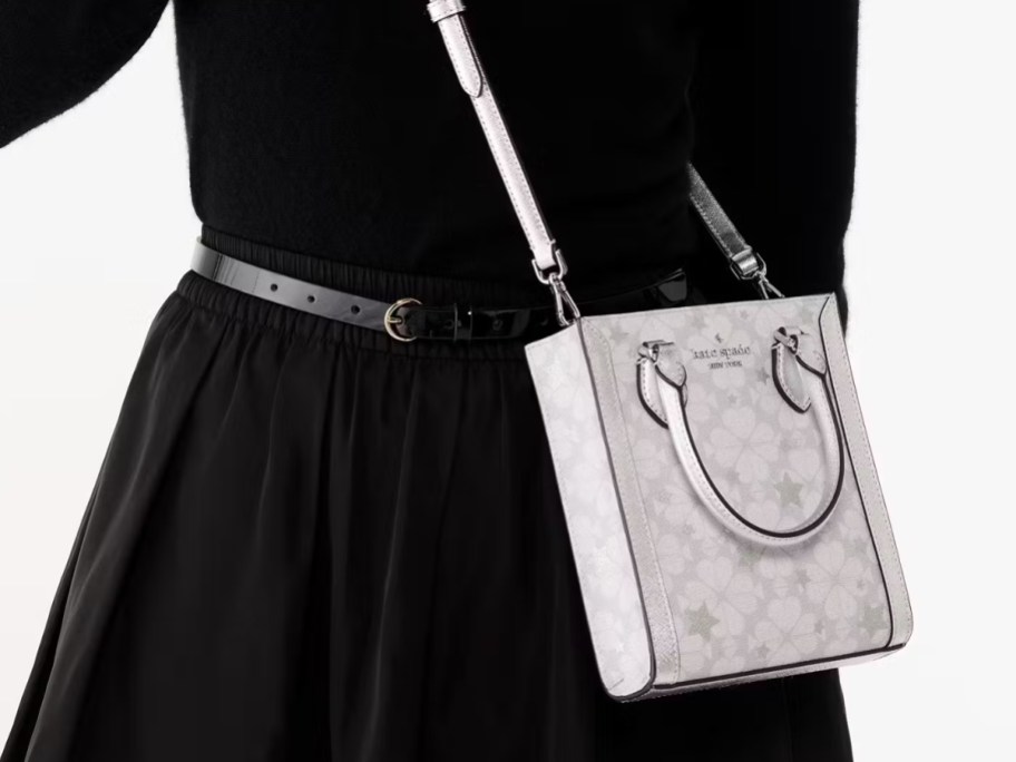 woman wearing a black dress, with a grey floral print crossbody bag