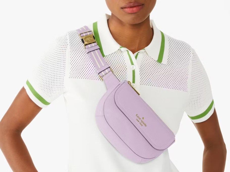 woman wearing a white polo style shirt with green accents, and a light purple belt bag worn as a crossbody bag