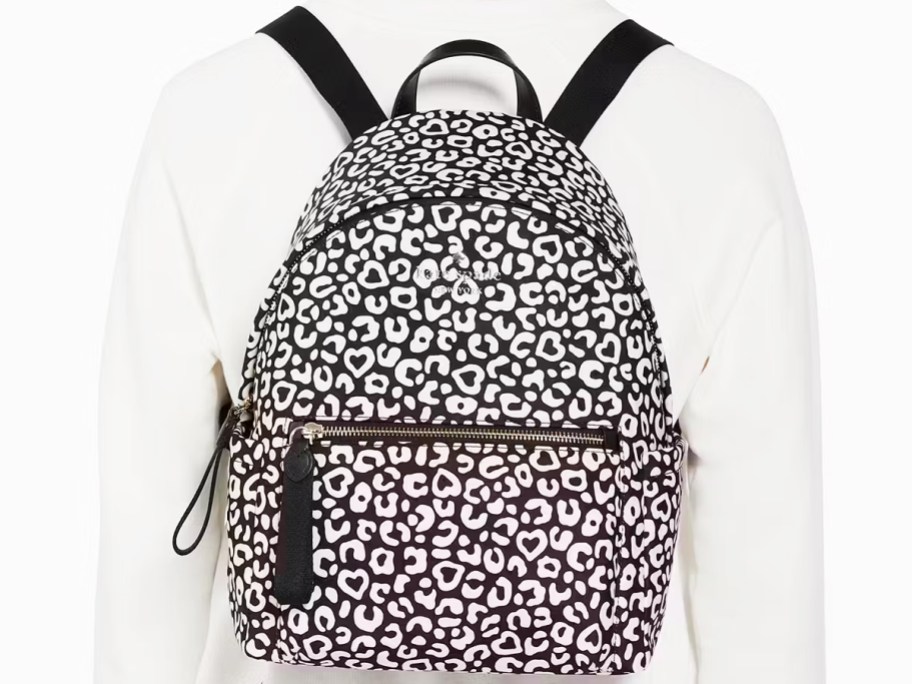 woman in a white sweater with a black and white leopard backpack