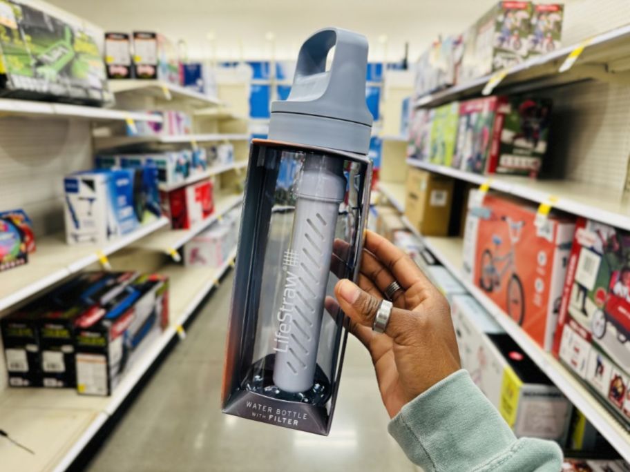 a womans hand holding a lifestraw filtered water bottle