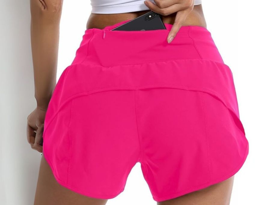 woman putting phone in back pocket of running shorts