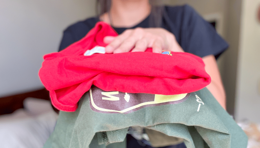 woman holding 2 graphic tshirts folded and stacked on top of each other