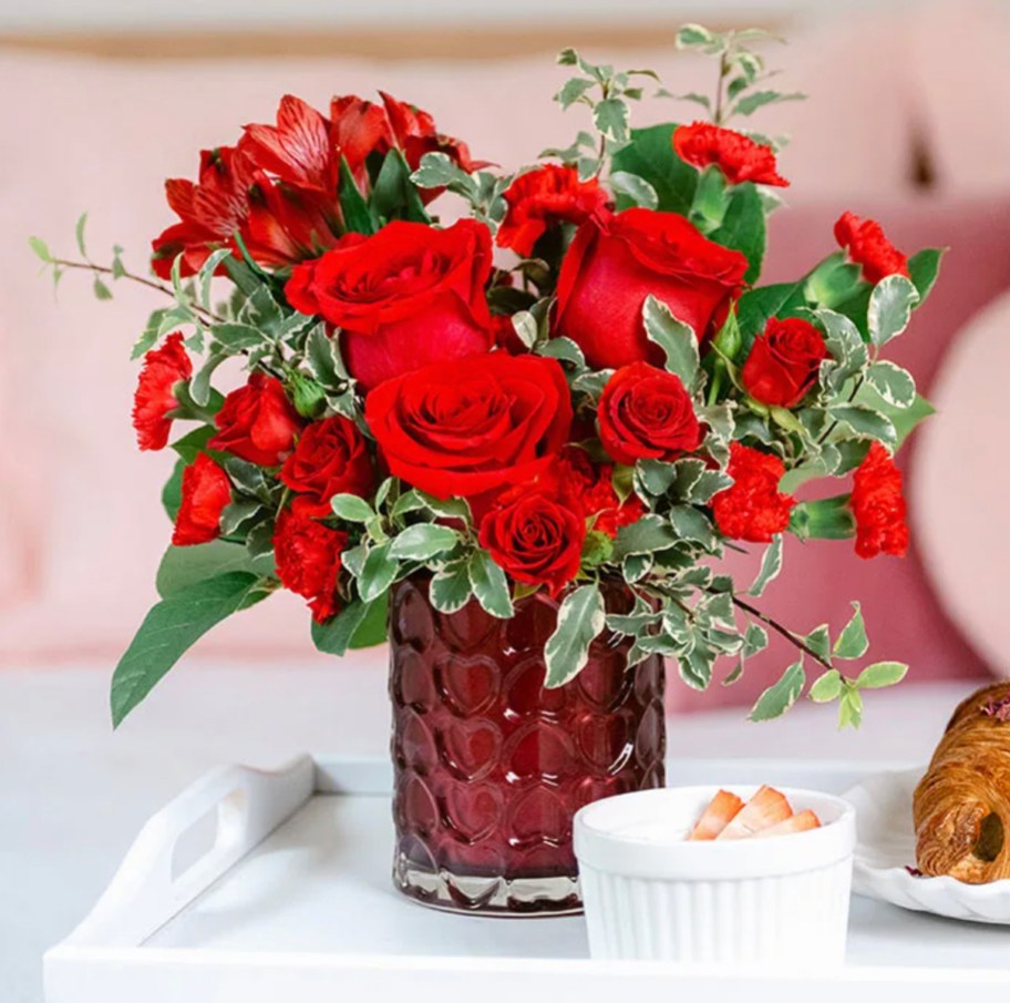 red heart vase with red roses inside