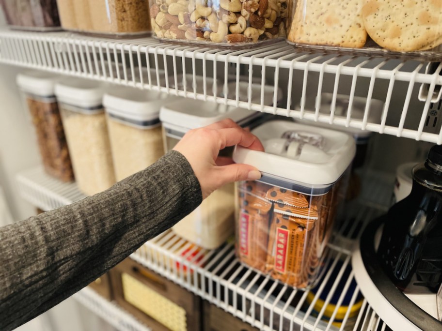 hand holding top of food container in organized pantry