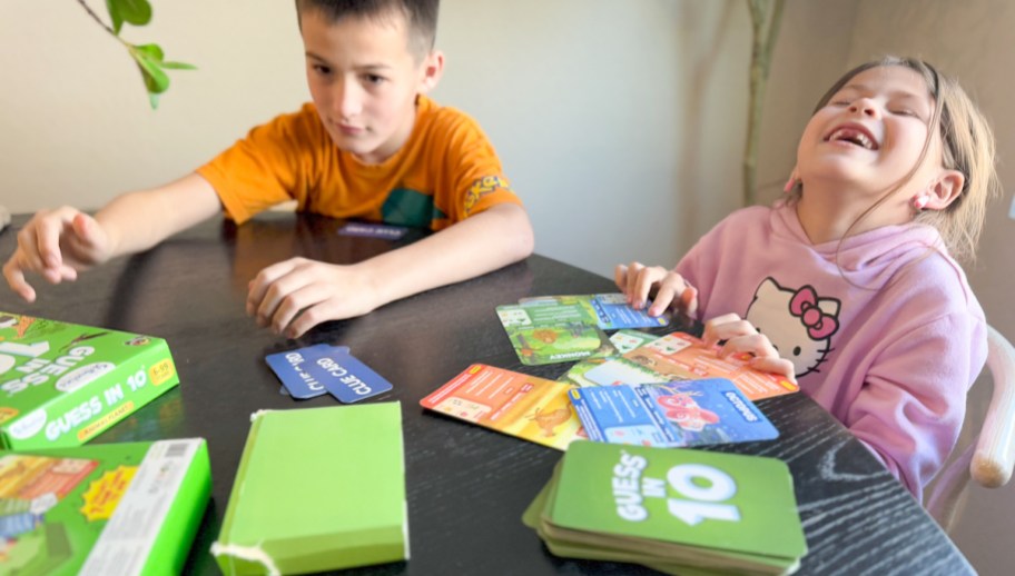 two kids sitting at table playing guess in 10 board game