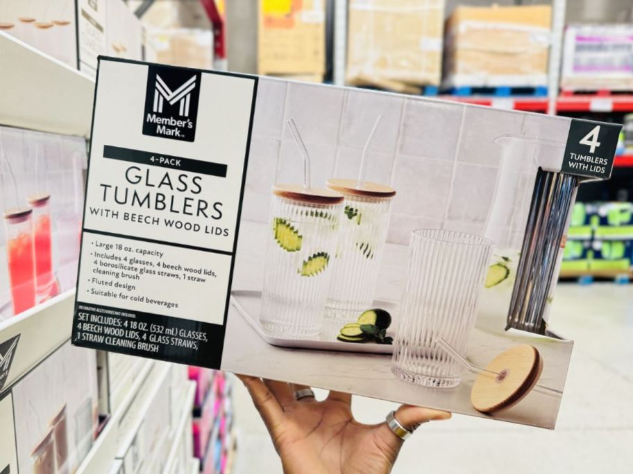 a womans hand holding a box of glass tumblers with lids