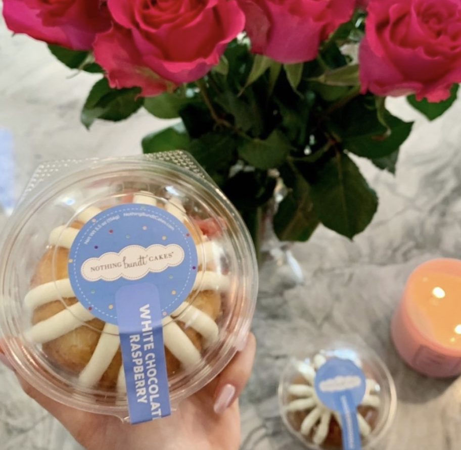 hand holding nothing bundt cakes bundtlet over kitchen counter with candle and flowers