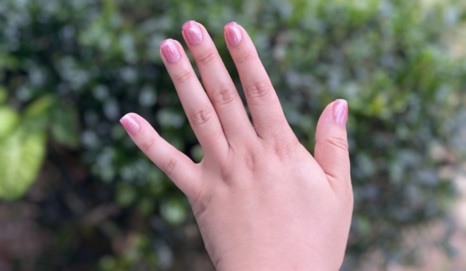 hand with press on nails over outdoor plants