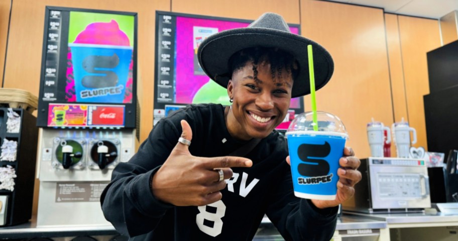 Person holding up blue Slurpee inside 7-Eleven s