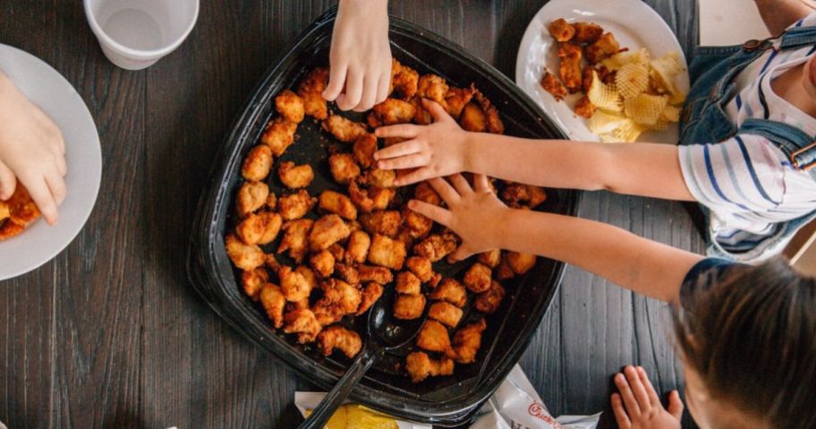 hands grabbing chicken nuggets from bowl