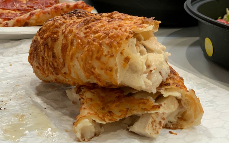 Costco Chicken Bake cut in half sitting on table, one of our favorite food deals