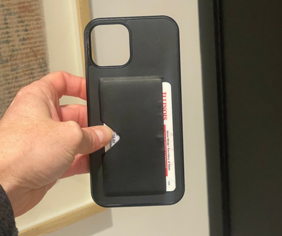 Hand holding out empty black phone case with wallet on back