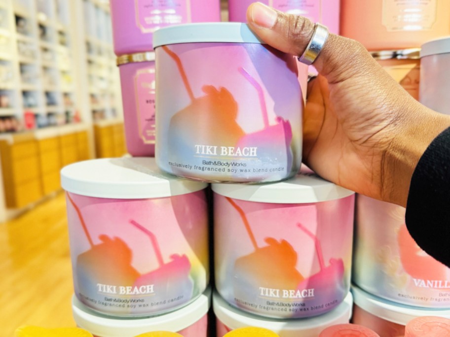 hand touching stack of tiki beach scented candles