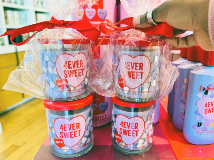 hand touching stack of valentine's day single wick candles at bath & body works