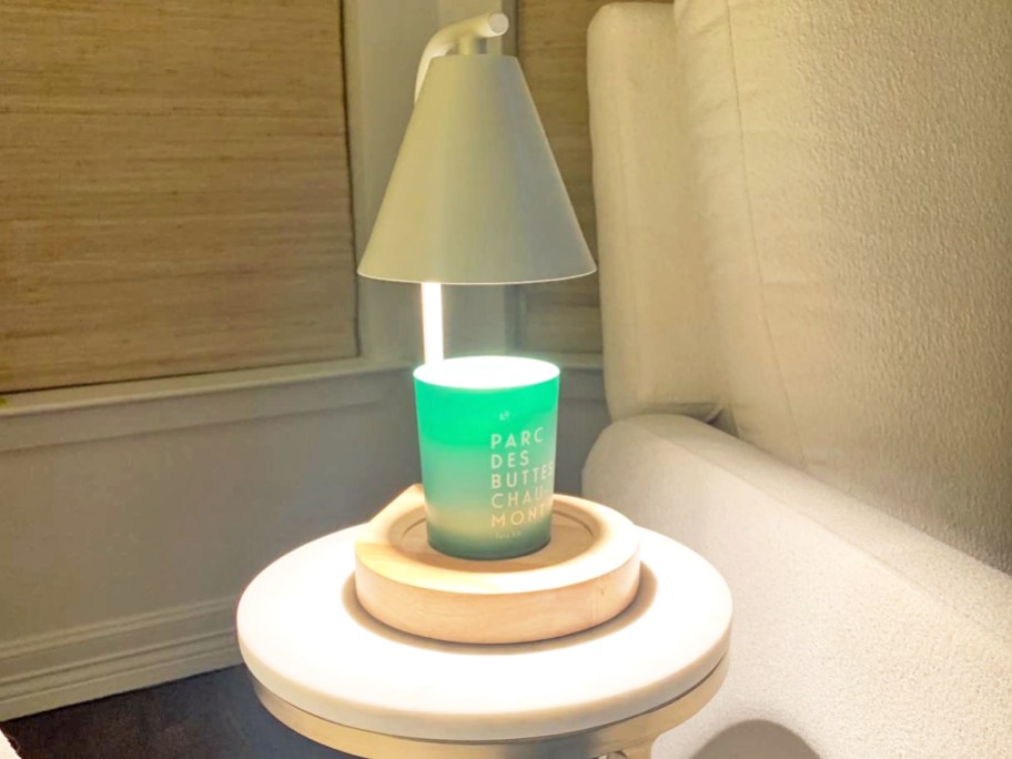 green candle under a white candle warmer lamp on side table