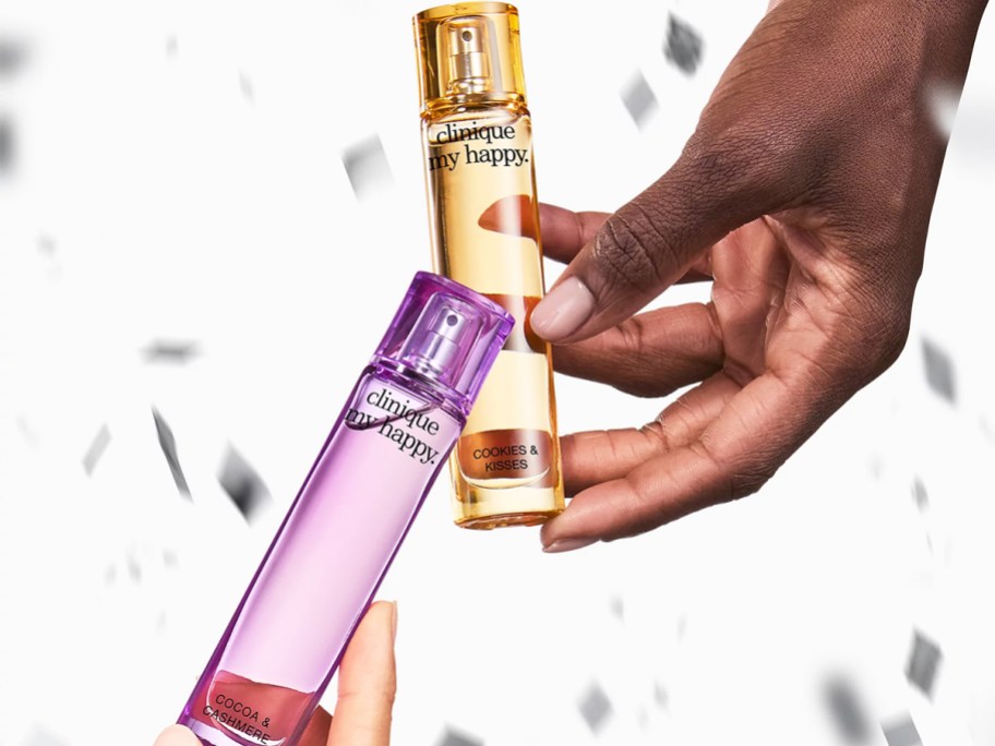 two hands holding bottles of clinique perfumes