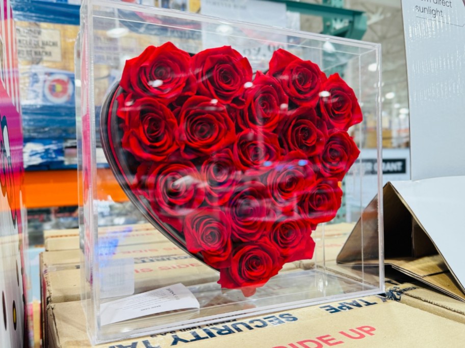 a clear plastic display case with a heart shaped box of red Forever Roses on display in a Costco store