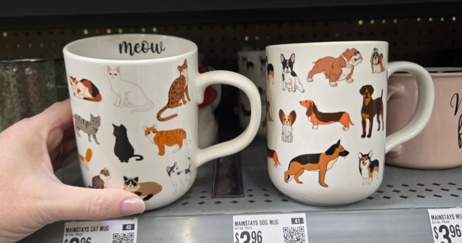 A person holding mugs with dogs and cats on them