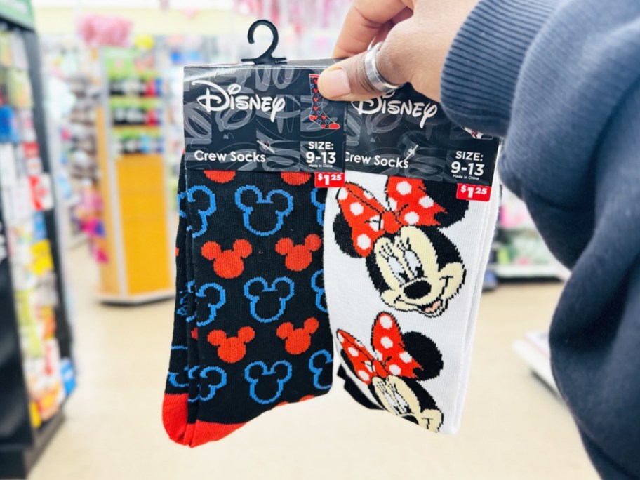 hand holding up two pairs of Disney Mickey & Minnie Crew Socks