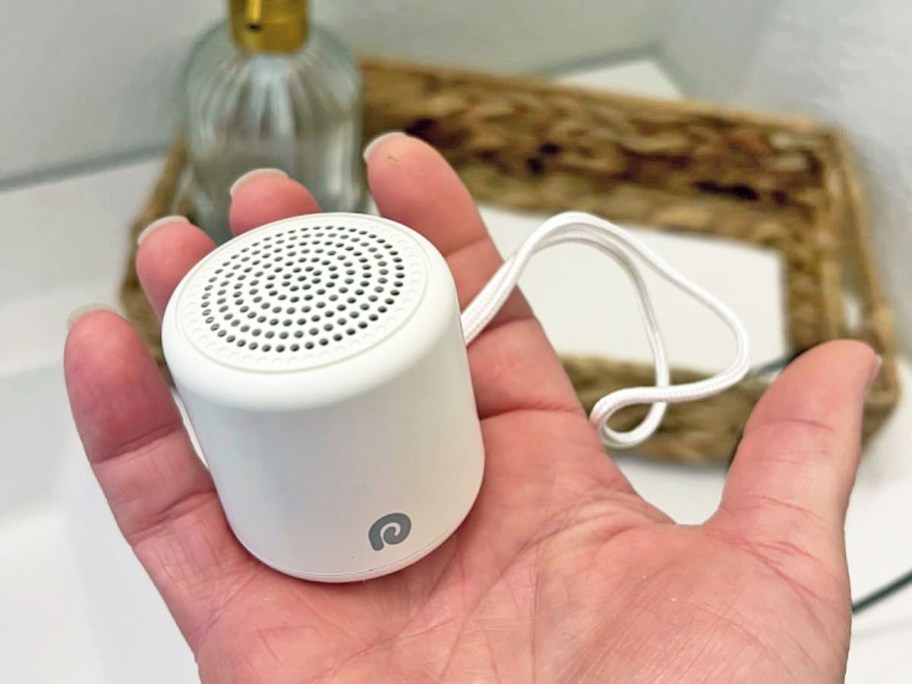 person holding a mini white noise machine in palm of hand