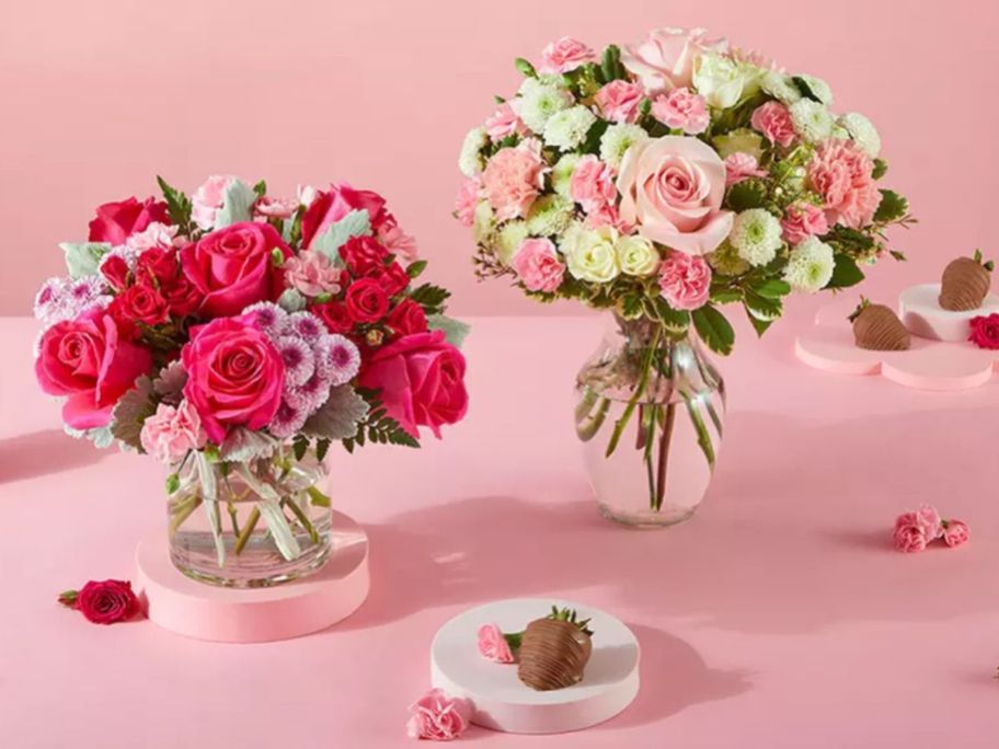 two vases of floral arranegments surrounded by chocolate covered strawberries