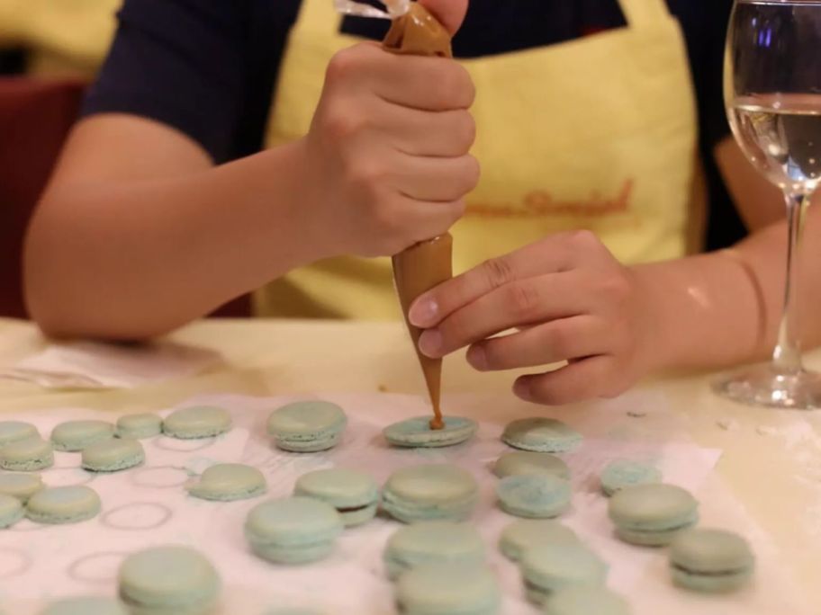 hands piping filling into macarons