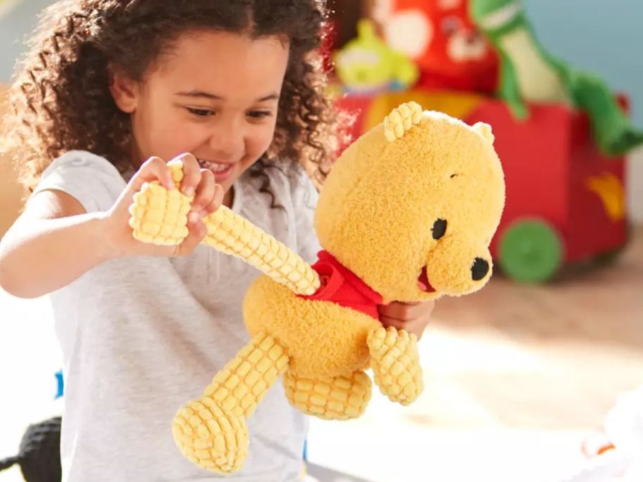 little girl pulling the arm of a Pooh Fidget Plush