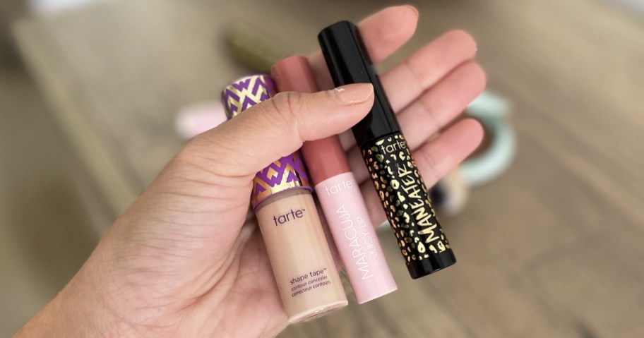 hand holding tarte mini mascara, shape tape, and lipstick