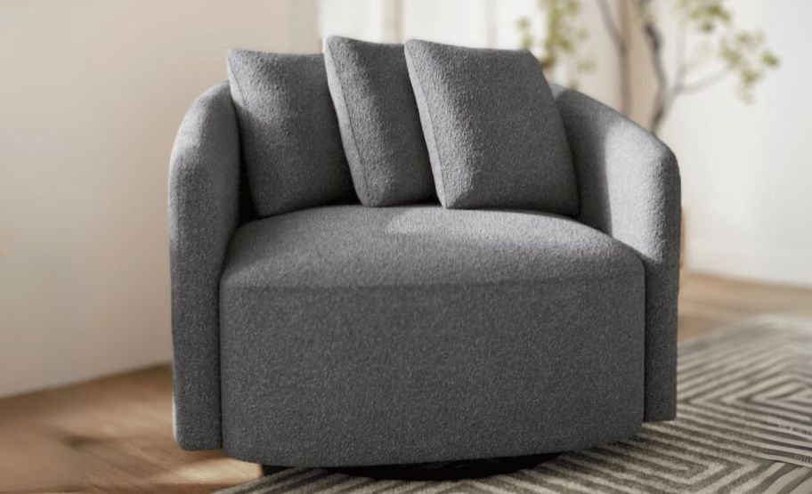 a charcoal colored boucle swivel chair in a living room on a rug