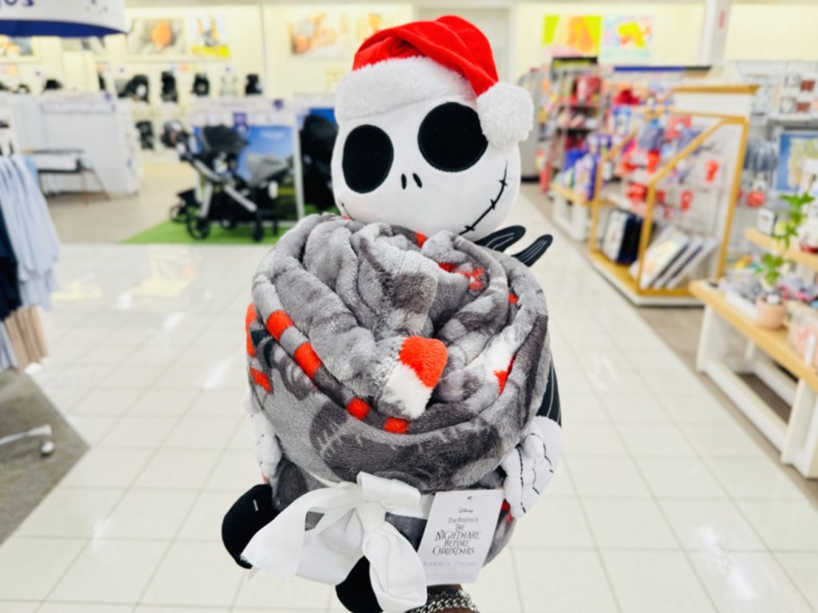 hand holding up a Jack Skellington plush and throw blanket set in store