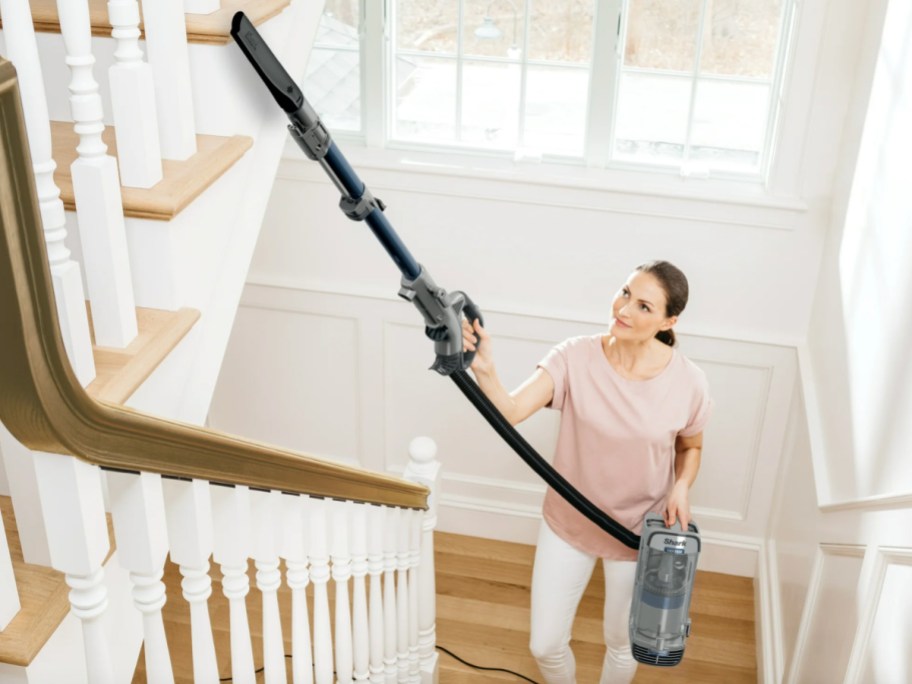 woman cleaning with vacuum nozzle up high