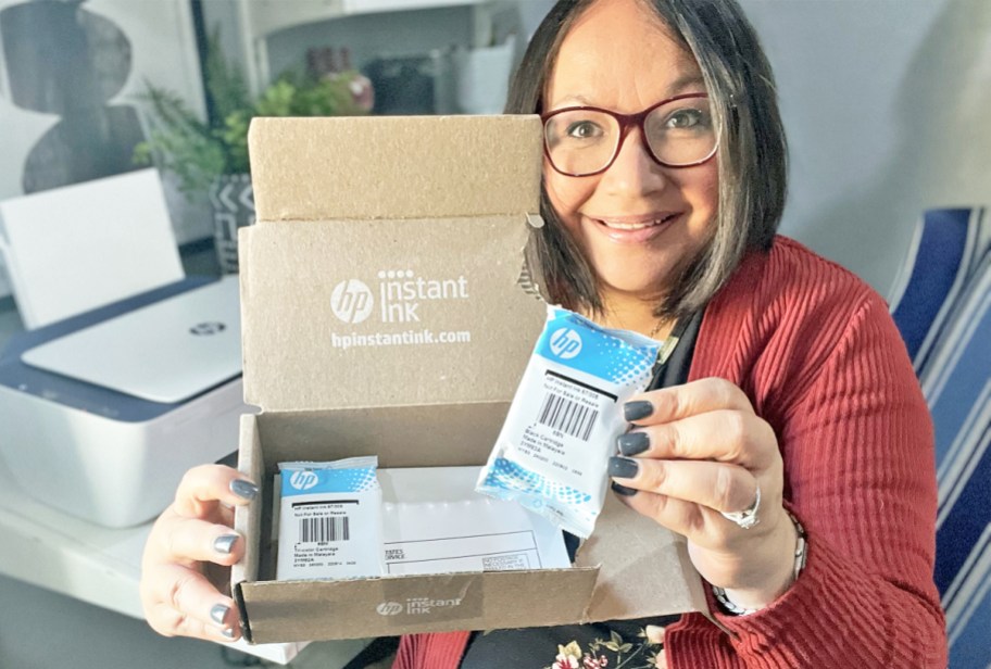 Woman holding up an HP Instant Ink box with ink refills