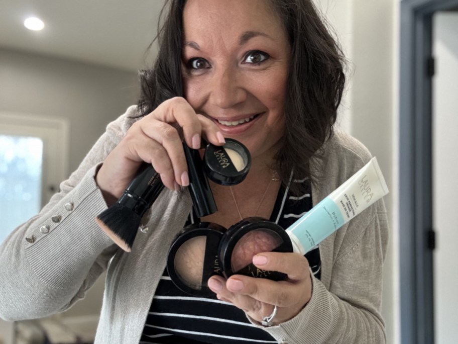 woman holding many makeup products