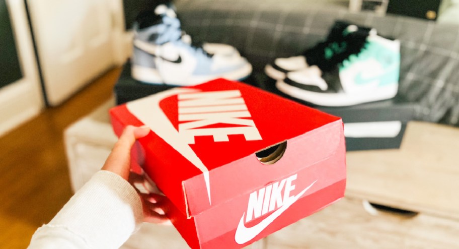 woman holding nike shoe box with nike shoes displayed in the background