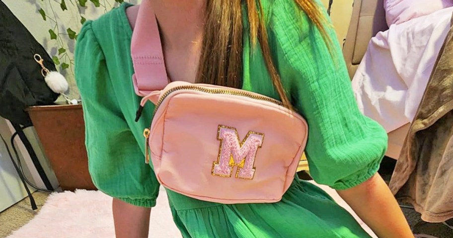 girl in green dress with a pink belt bag across chest