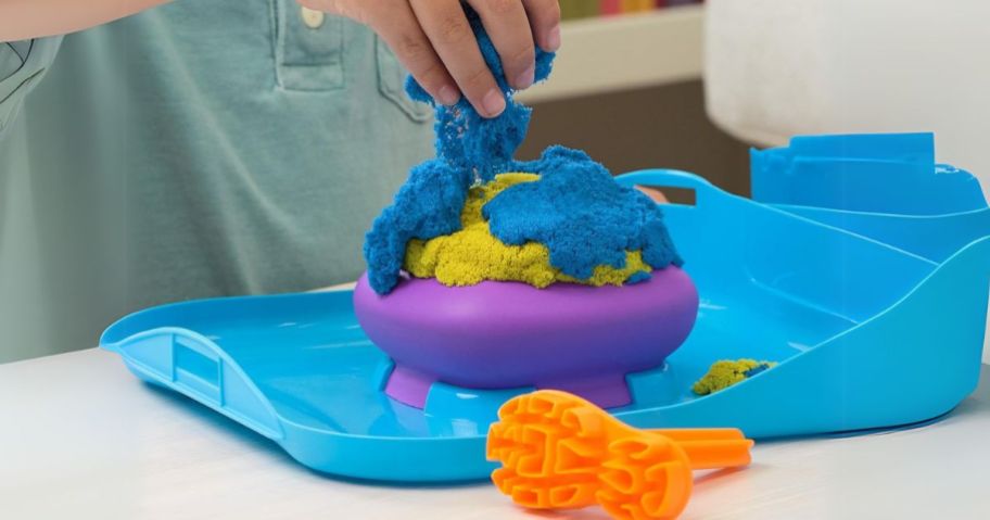 hand playing with Kinetic Sand Squishmotion Playset