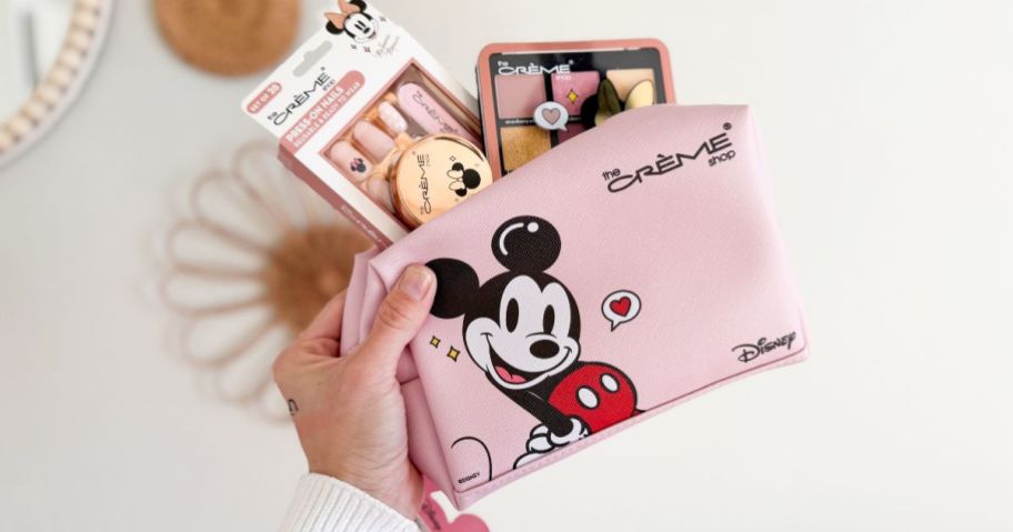 A person holding a Mickey Mouse travel cosmetics bag